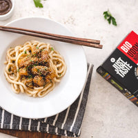 Bord udon noedels met krokante kip, sesam en bosui, klaargemaakt in de wok