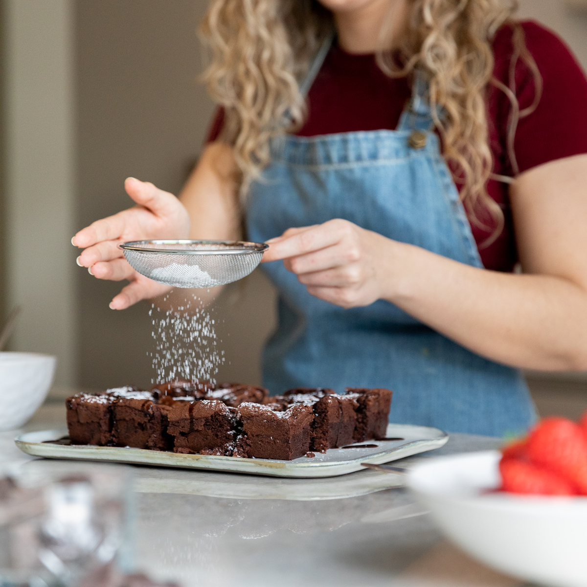 Lisa bestrooit verse brownies met erythritol via een zeefje
